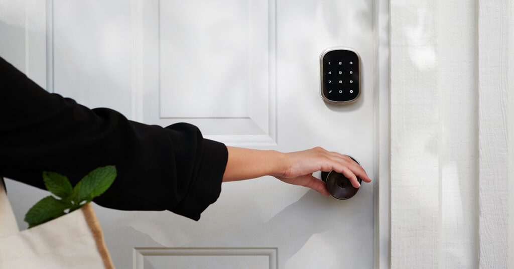 Person attempting to open a locked front door with a smart lock, emphasizing the need for robust wifi security in the digital realm. Protect your online home from potential intruders.